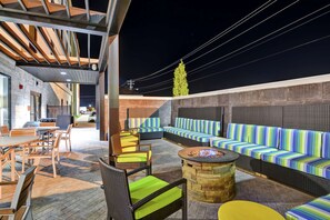 An outdoor patio area with seating, a fire pit, and a view of the city at night. - Home2 Suites by Hilton Conway (Conway)