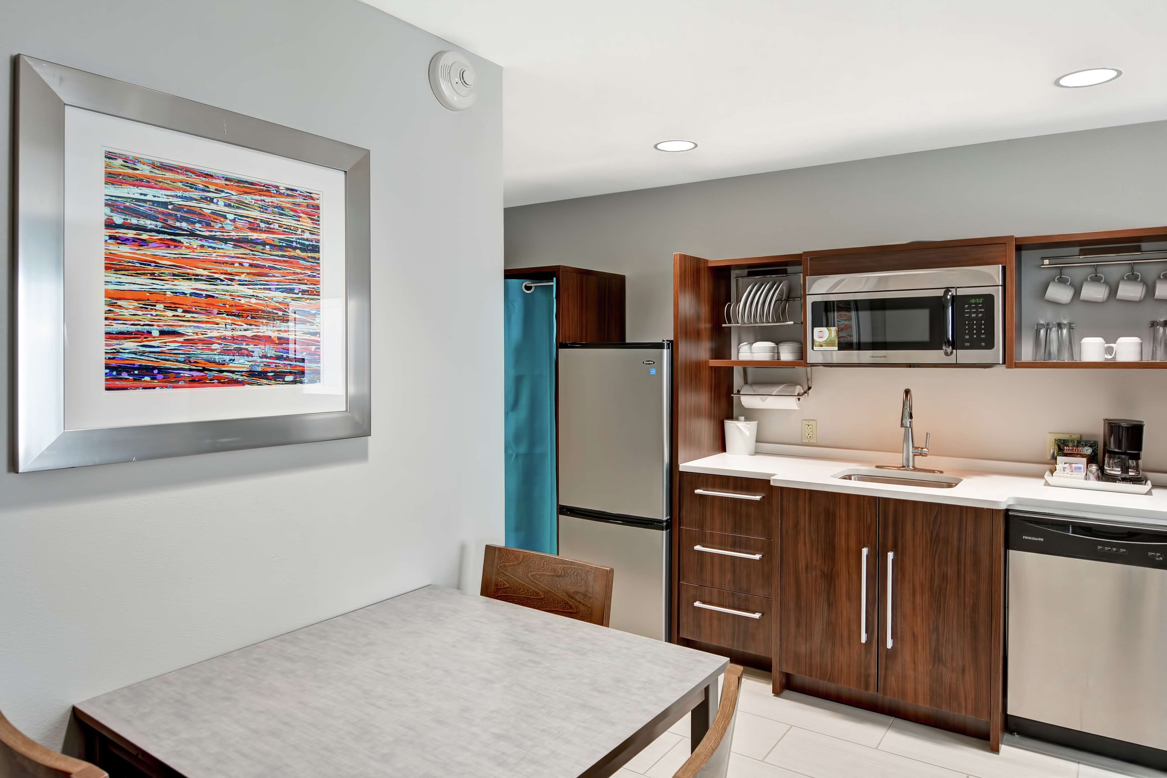 A modern kitchen with a microwave, refrigerator, and wooden cabinets.