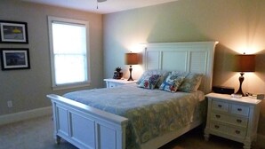 A bedroom with a bed, nightstands, a window, and wall-mounted lamps.