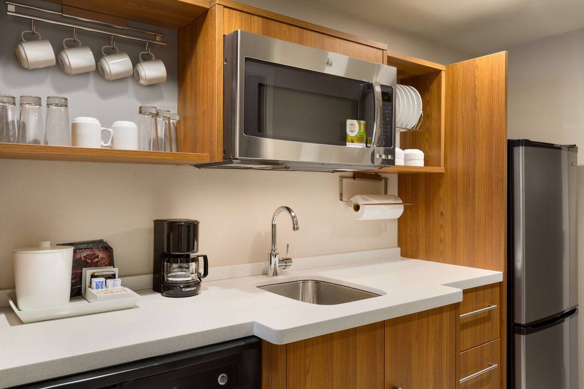 A modern kitchen with a stainless steel microwave, coffee maker, and refrigerator.