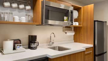 A modern kitchen with a stainless steel microwave, coffee maker, and refrigerator.