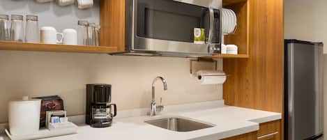Una cocina moderna con microondas de acero inoxidable, cafetera y refrigerador.