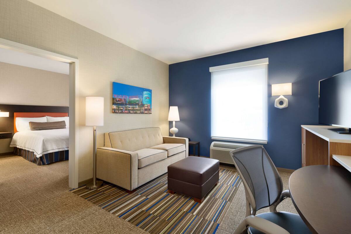 A hotel room with a bed, a sofa, a desk, and a chair.