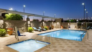 An outdoor swimming pool with a pergola, lounge chairs, and potted plants.