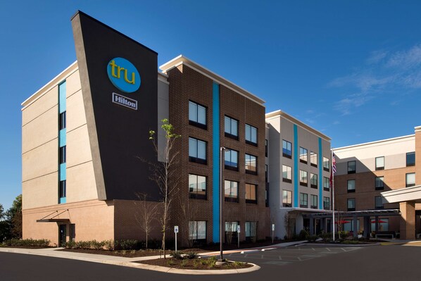 Un hotel moderno con un llamativo letrero 'tru Hilton', fachada de ladrillo y un estacionamiento.