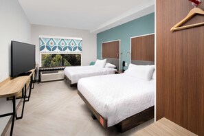 Habitación de hotel moderna con dos camas, un escritorio, un televisor y una ventana con vistas a zonas verdes.