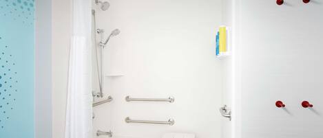 A modern bathroom with a bathtub, shower, and handrails.