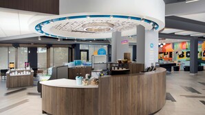 A modern reception area with a central counter, a coffee station, and a seating area. - Tru by Hilton Murfreesboro (Murfreesboro)