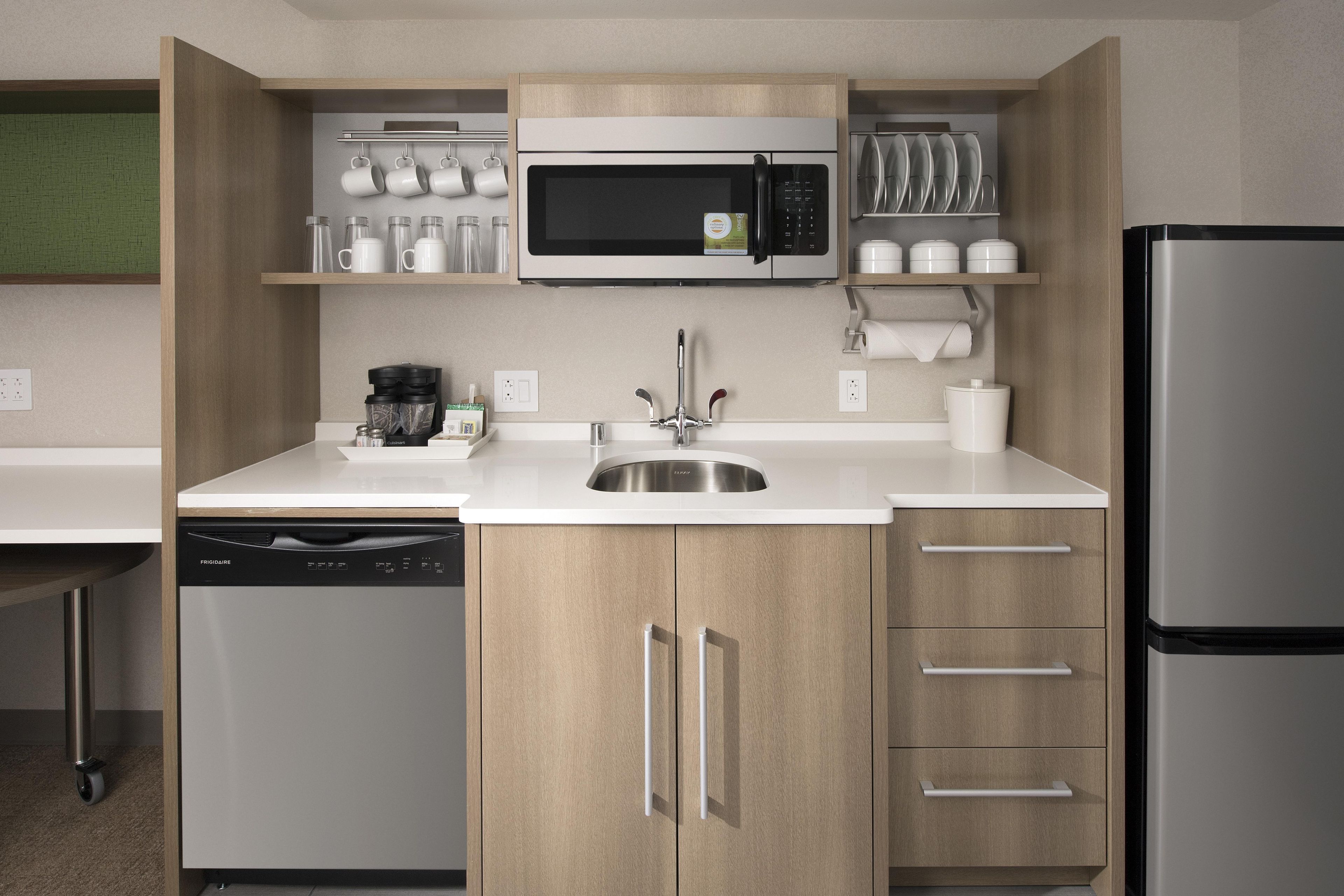 A compact kitchen with a built-in microwave, a coffee maker, and a dishwasher.