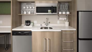 A compact kitchen with a built-in microwave, a coffee maker, and a dishwasher.