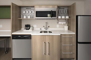 A compact kitchen with a built-in microwave, a coffee maker, and a dishwasher. - Home2 Suites by Hilton Murfreesboro (Murfreesboro)