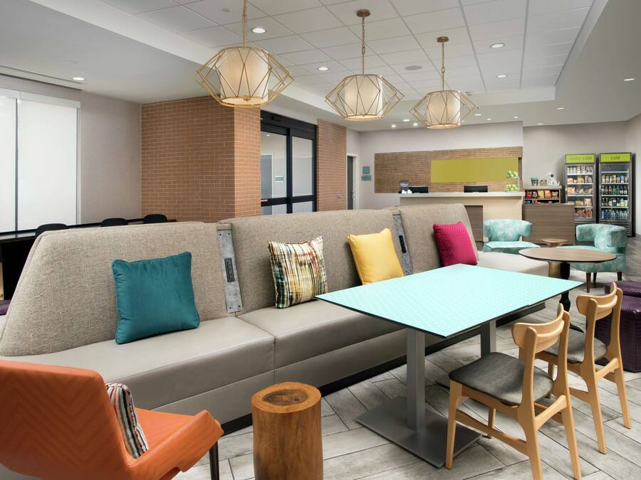 Un espacio lounge moderno con sofá, sillas, una mesa y un refrigerador.