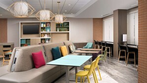 A modern lounge area with a sofa, chairs, a table, and a TV. - Home2 Suites by Hilton Murfreesboro (Murfreesboro)
