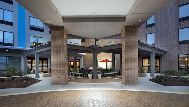 A multi-level outdoor patio area with seating and planters, surrounded by modern buildings with large windows. - Home2 Suites by Hilton Murfreesboro (Murfreesboro)