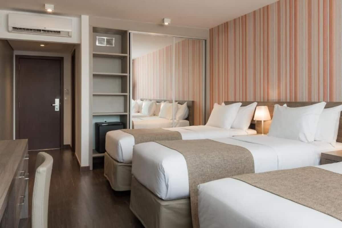 A hotel room with three beds, a desk, and a wardrobe.