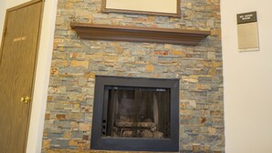 Une cheminée en pierre avec un téléviseur encastré, une porte en bois et une plaque indiquant le nom de la pièce.