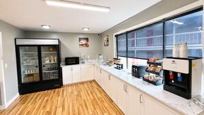 Une cuisine moderne équipée d’un réfrigérateur, d’un four à micro-ondes, d’une machine à café et d’une grande fenêtre.