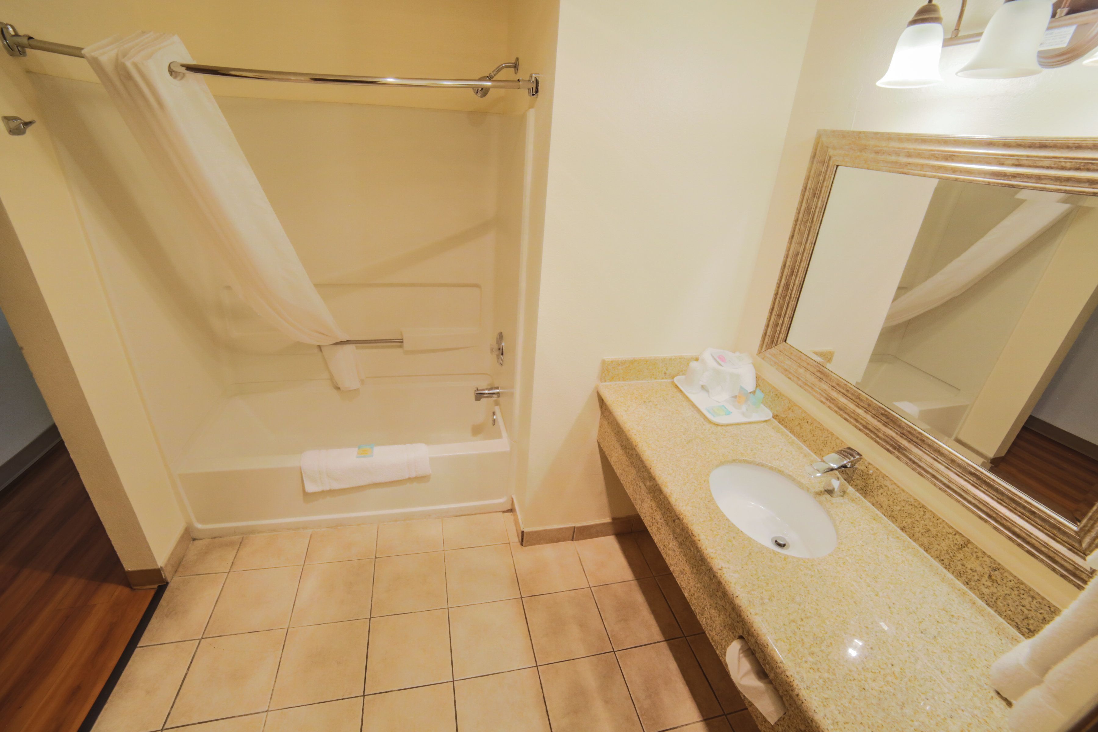 A bathroom with a bathtub, a sink, a mirror, and a towel rack.
