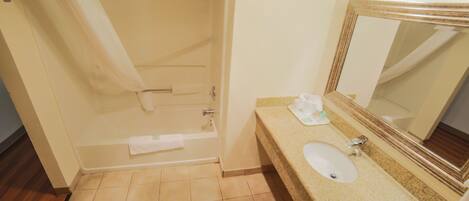A bathroom with a bathtub, a sink, a mirror, and a towel rack.