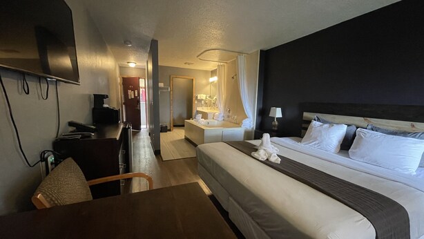 Une chambre d’hôtel équipée d’un lit, d’une table de chevet, d’une lampe et d’un téléviseur fixé au mur.