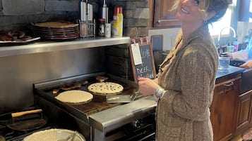 Una cocina con pared de piedra, una plancha y una persona cocinando.