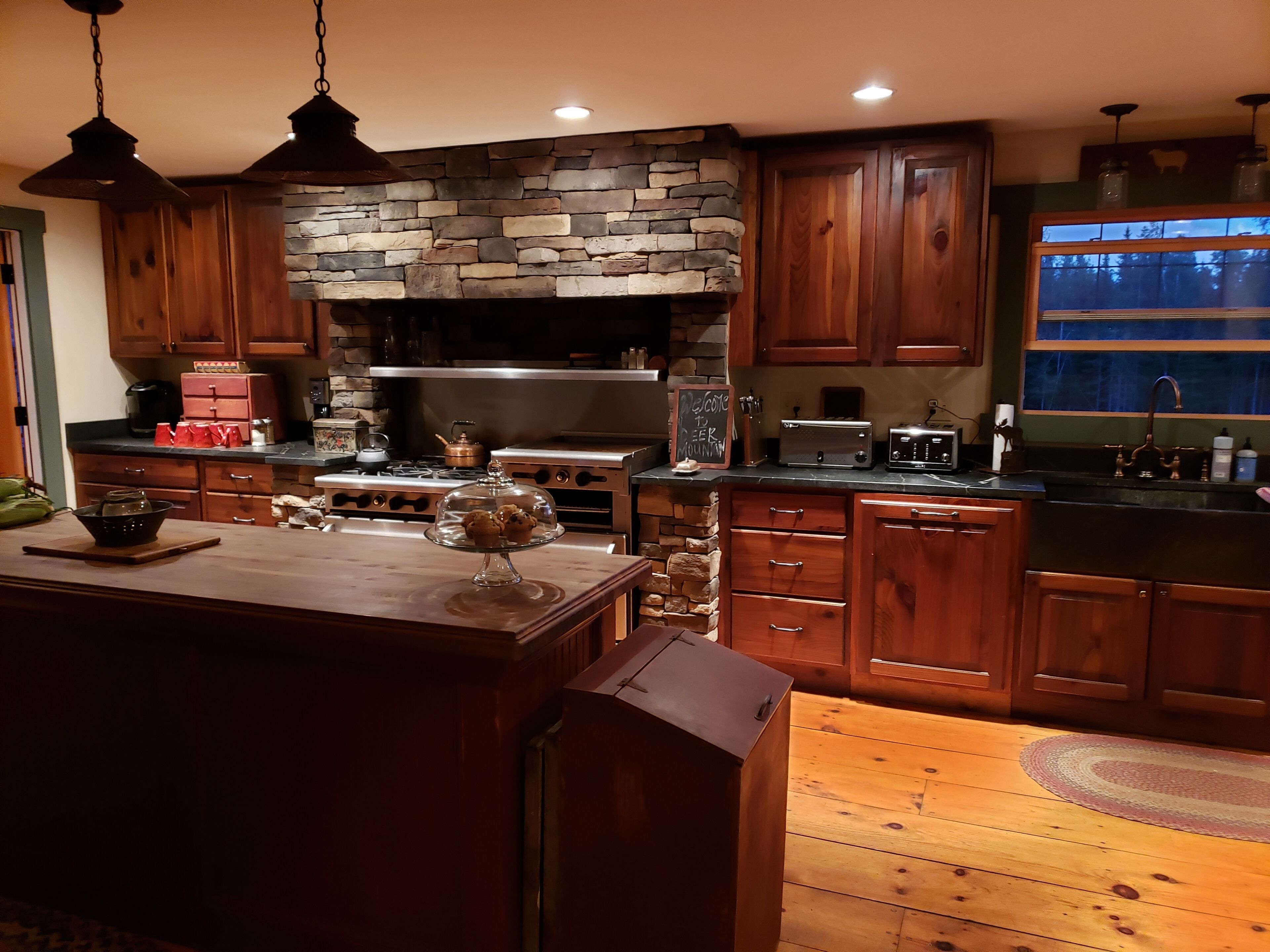 A kitchen with wooden cabinets, a stone accent wall, a stove, and a toaster.