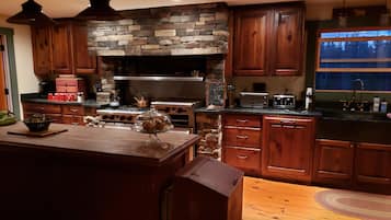 A kitchen with wooden cabinets, a stone accent wall, a stove, and a toaster.