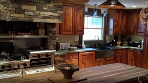 A kitchen with wooden cabinets, a stone accent wall, an Imperial stove, and a large window.
