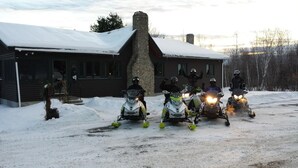 A group of snowmobiles parked in front of a log cabin with a stone chimney.