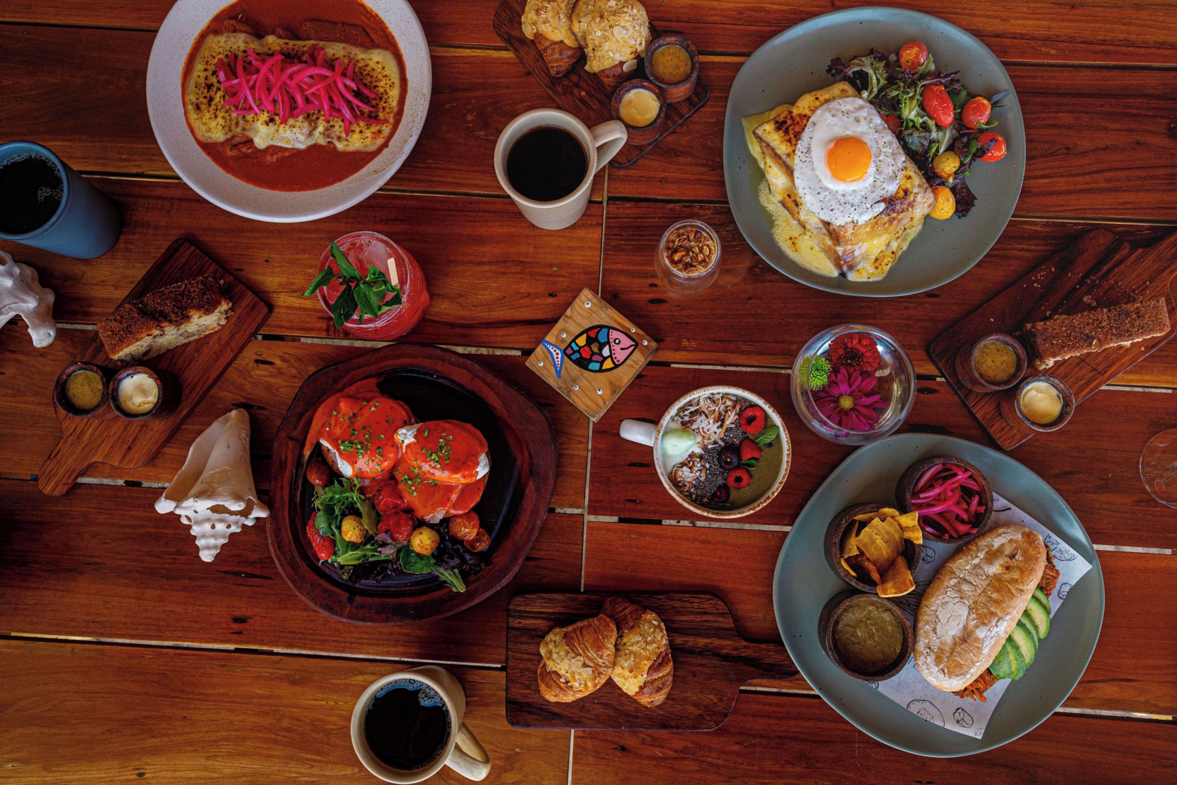 Una mesa de madera con diferentes platos, incluyendo un plato de comida, una taza de café y un tazón de ensalada.