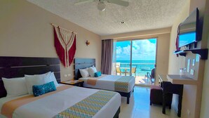 Ein Hotelzimmer mit zwei Betten, einem Schreibtisch, einem Fernseher und Meerblick.