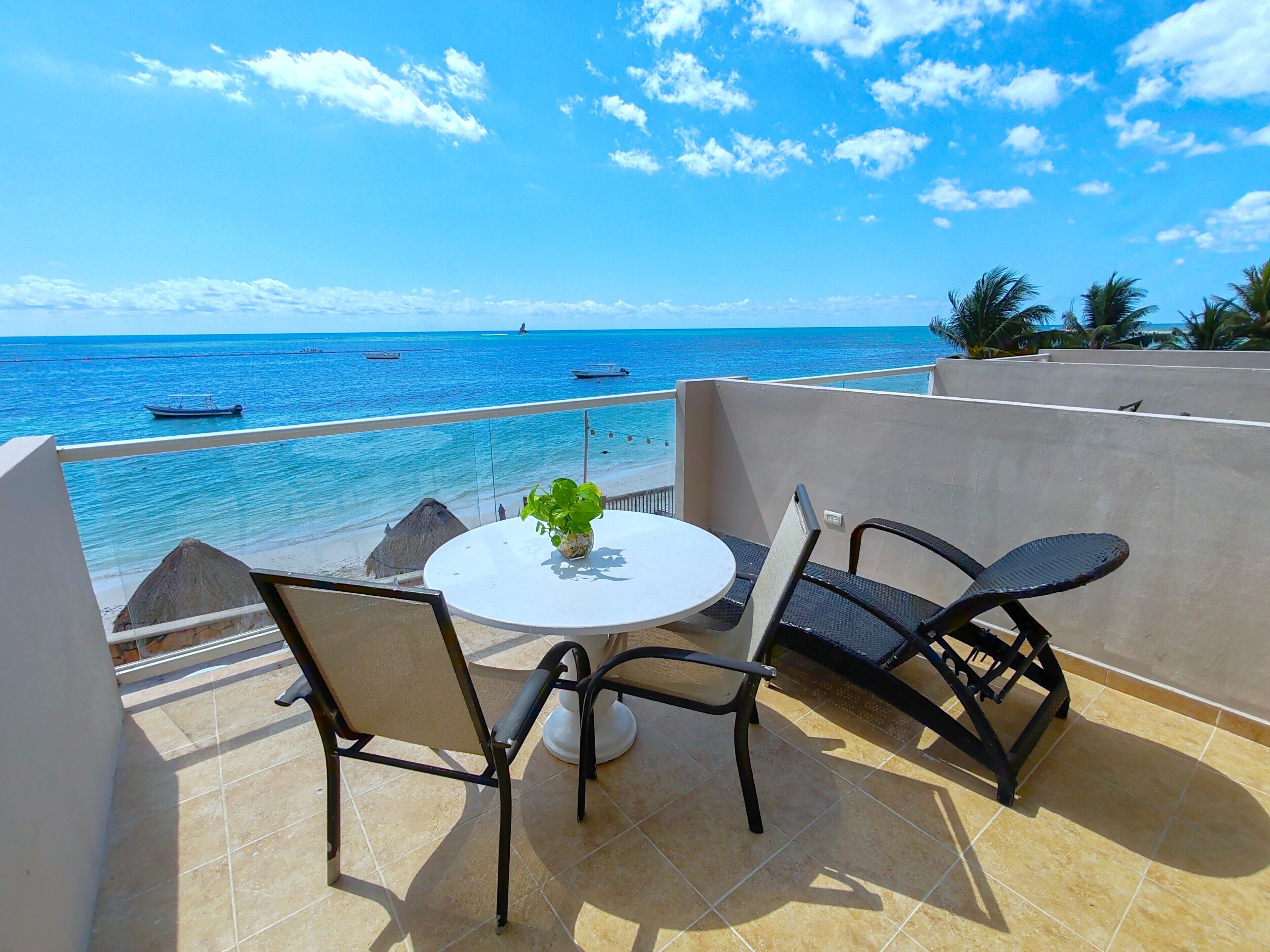 A balcony with a round table, two chairs, and a potted plant.