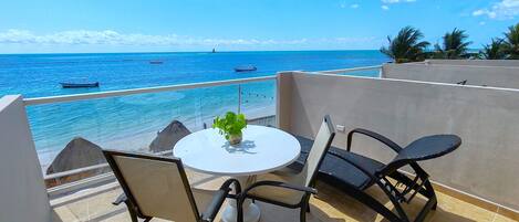 A balcony with a round table, two chairs, and a potted plant.