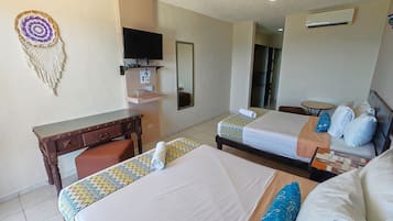 A hotel room with two beds, a desk, a television, and a ceiling fan.