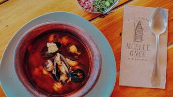 Uma tigela de sopa de marisco sobre uma mesa, com uma colher e um menu.