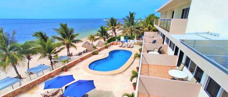 A resort with a swimming pool, lounge chairs, and a view of the ocean.