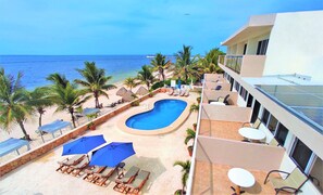 Enjoy ocean views from the resort's pool area, surrounded by lounge chairs and umbrellas, with access to the sandy beach and palm trees.