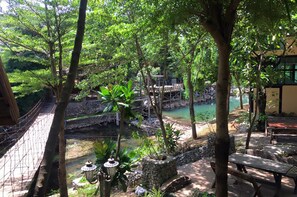 A serene outdoor area with a wooden bridge, stone structures, and a tranquil water body surrounded by lush greenery. - Khaoyai Kirithantip Resort (Pak Chong)