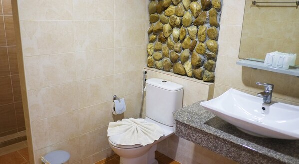 A bathroom with a toilet, a sink, and a stone wall. - Khaoyai Kirithantip Resort (Pak Chong)