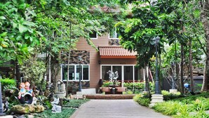 A pathway leading to a building with a tiled roof, surrounded by lush greenery and decorative statues. - Khaoyai Kirithantip Resort (Pak Chong)