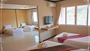 A hotel room with two beds, a sofa, a television, and a window with a view of greenery. - Khaoyai Kirithantip Resort (Pak Chong)