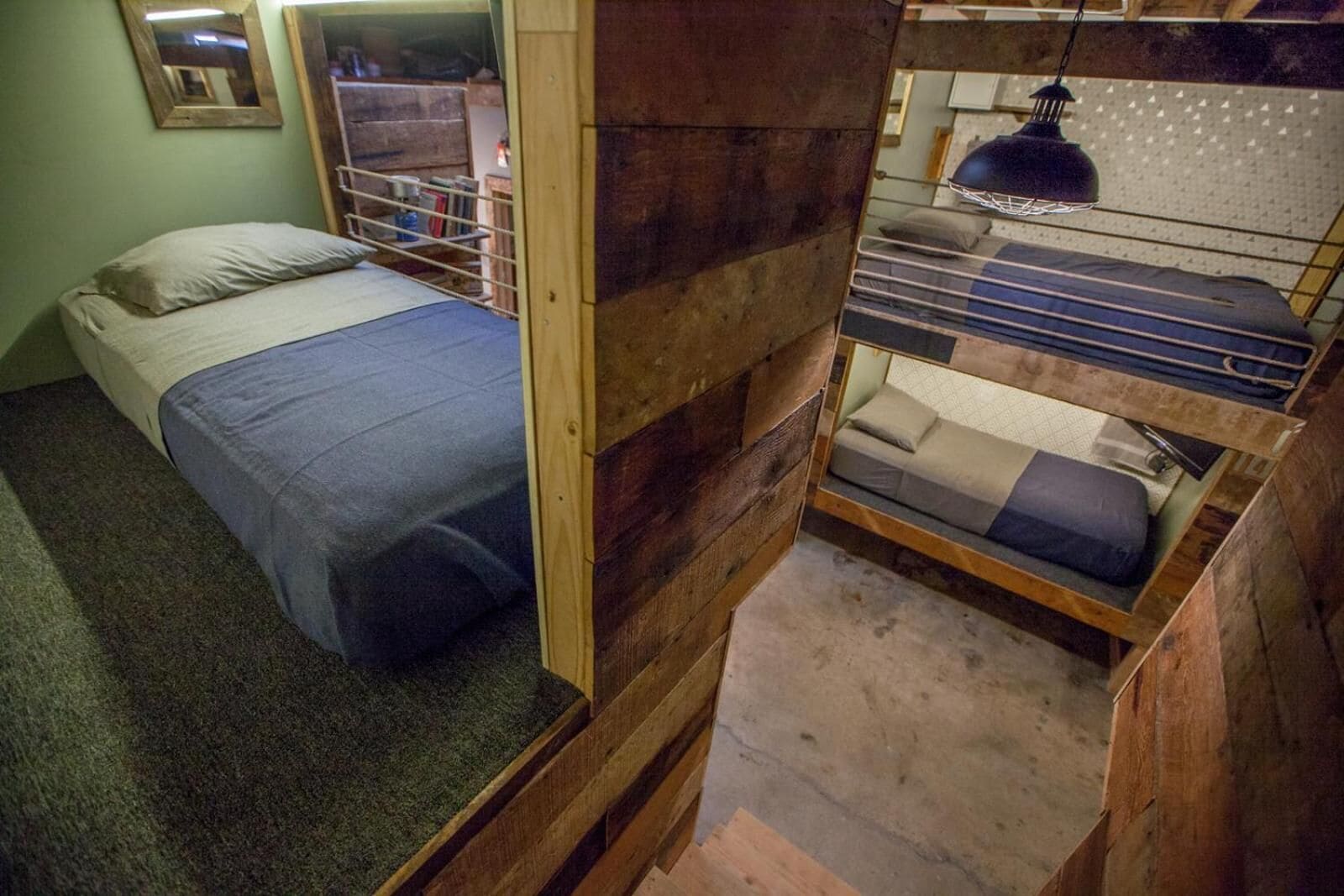 A compact room with a bunk bed, a single bed, and a small desk area.