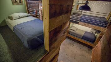 A compact room with a bunk bed, a single bed, and a small desk area.