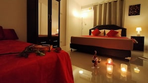 Een hotelkamer met een bed, nachtkastje, spiegel en een tafel met kaarsen.