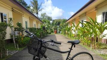 A bicycle parked on a paved path between two yellow buildings with a clear sky above.