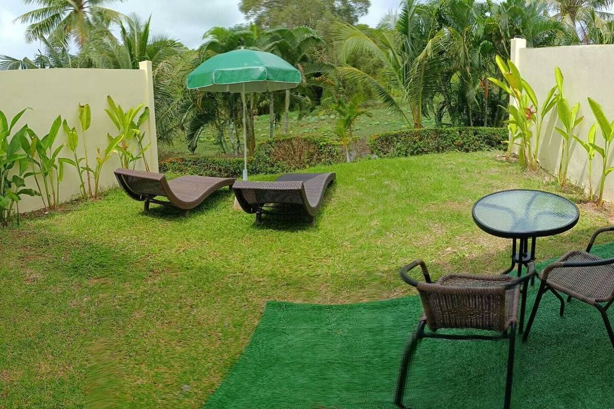 A patio area with two lounge chairs, a small table, and a green umbrella.