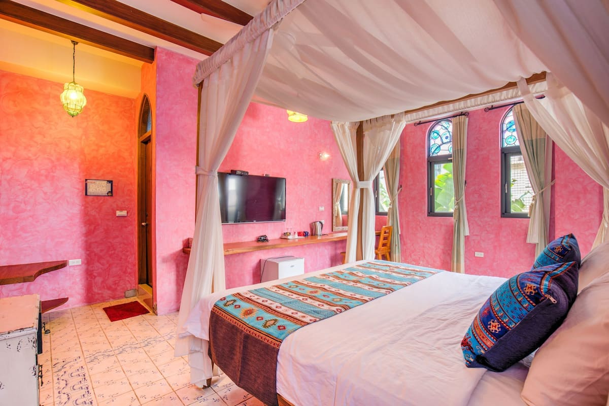 A room with a bed, a television, and a desk.