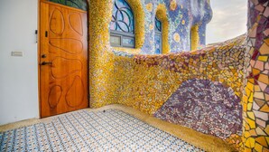 A room with a mosaic wall, a wooden door, and a tiled floor.