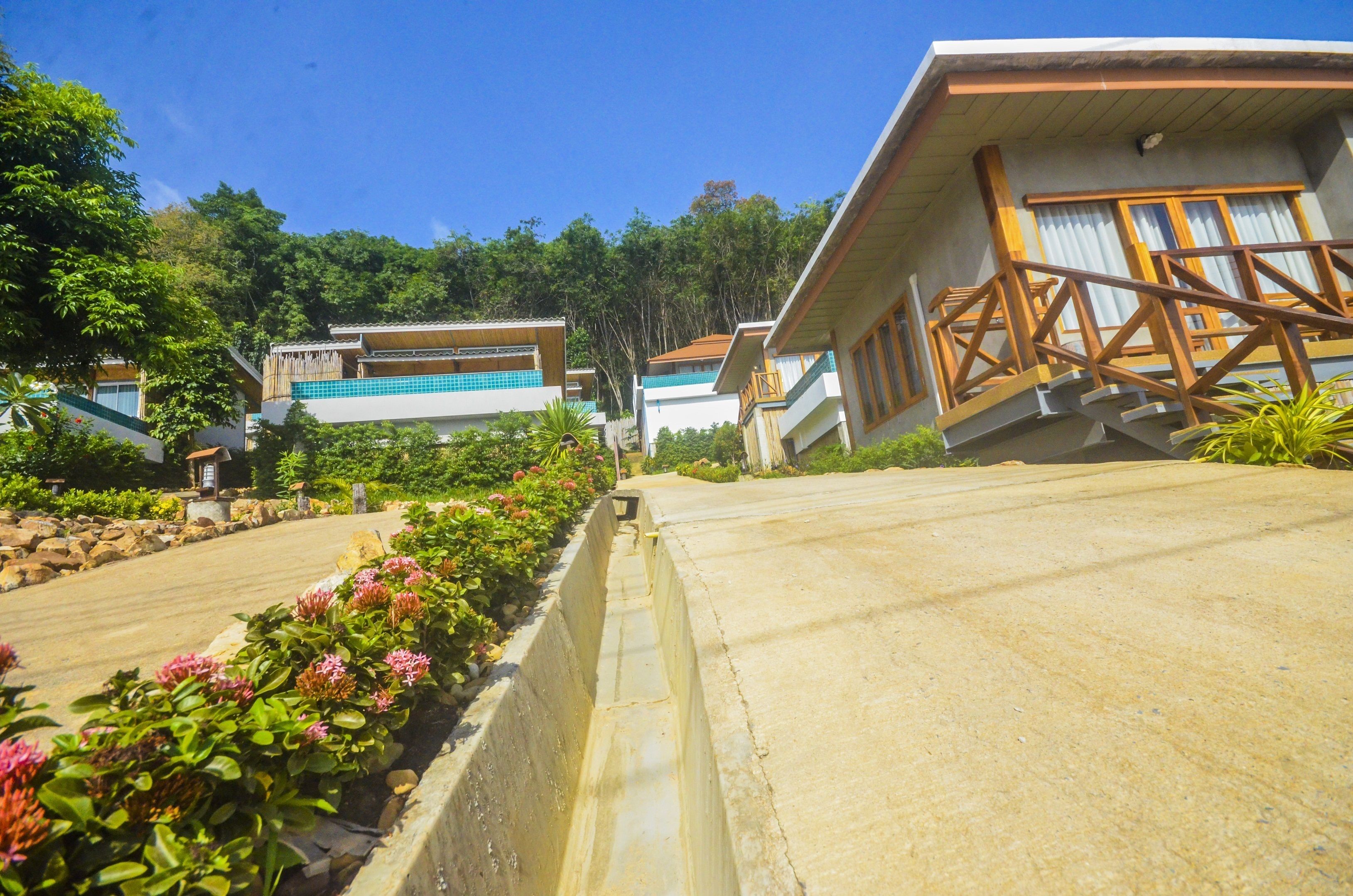 A residential area with houses, a concrete pathway, and a small pool.