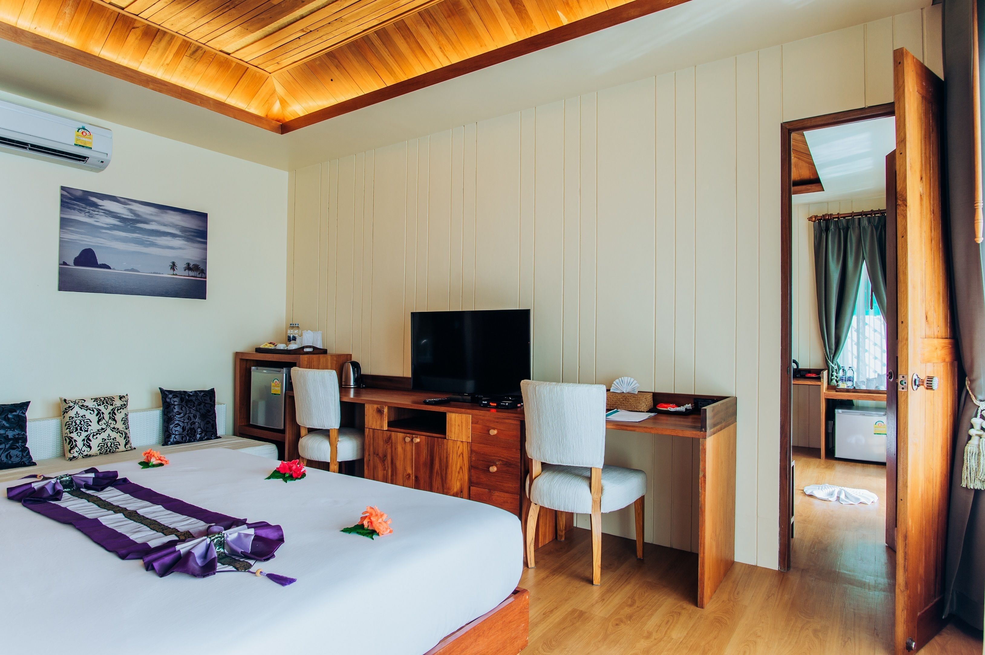 Habitación de hotel con cama, escritorio, televisión y vista al mar por la ventana.